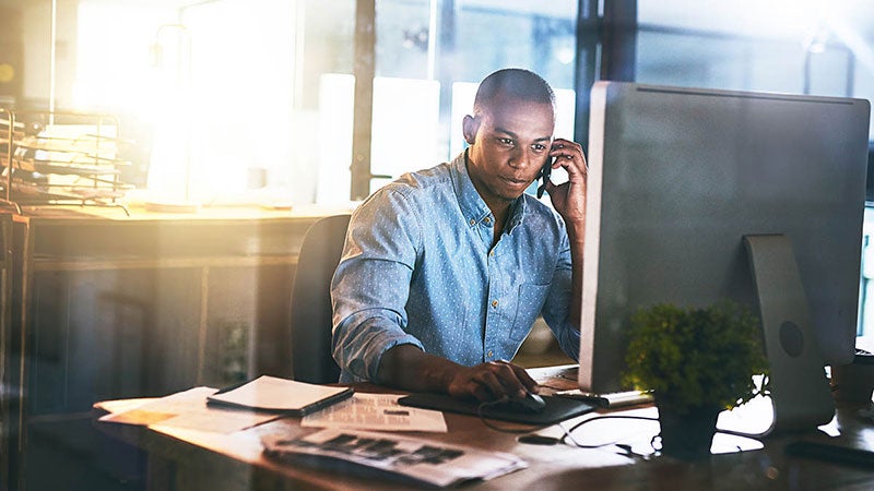 Person working their desktop while talking on the phone