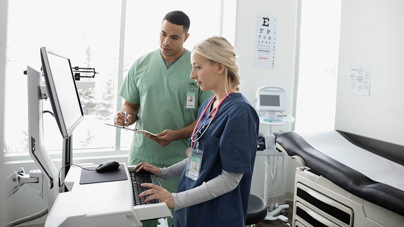 A doctor and nurse looking at a computer in an examination room