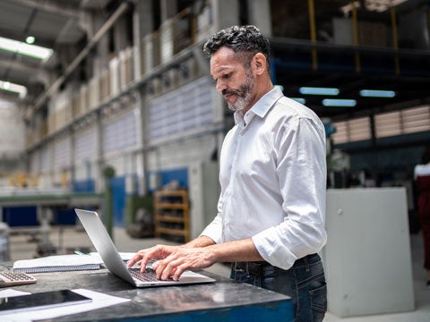 Person typing on a laptop in a warehouse