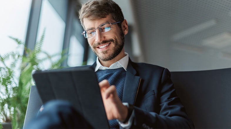 Business professional sitting on a couch while using a tablet