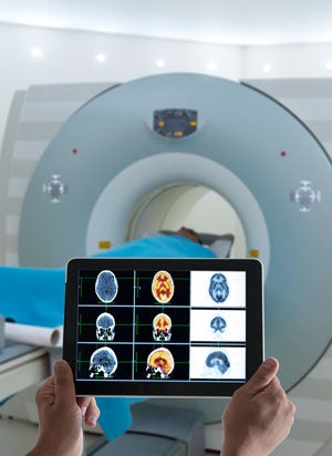 Doctor looking at MRI results on a tablet in front of a patient in an MRI machine