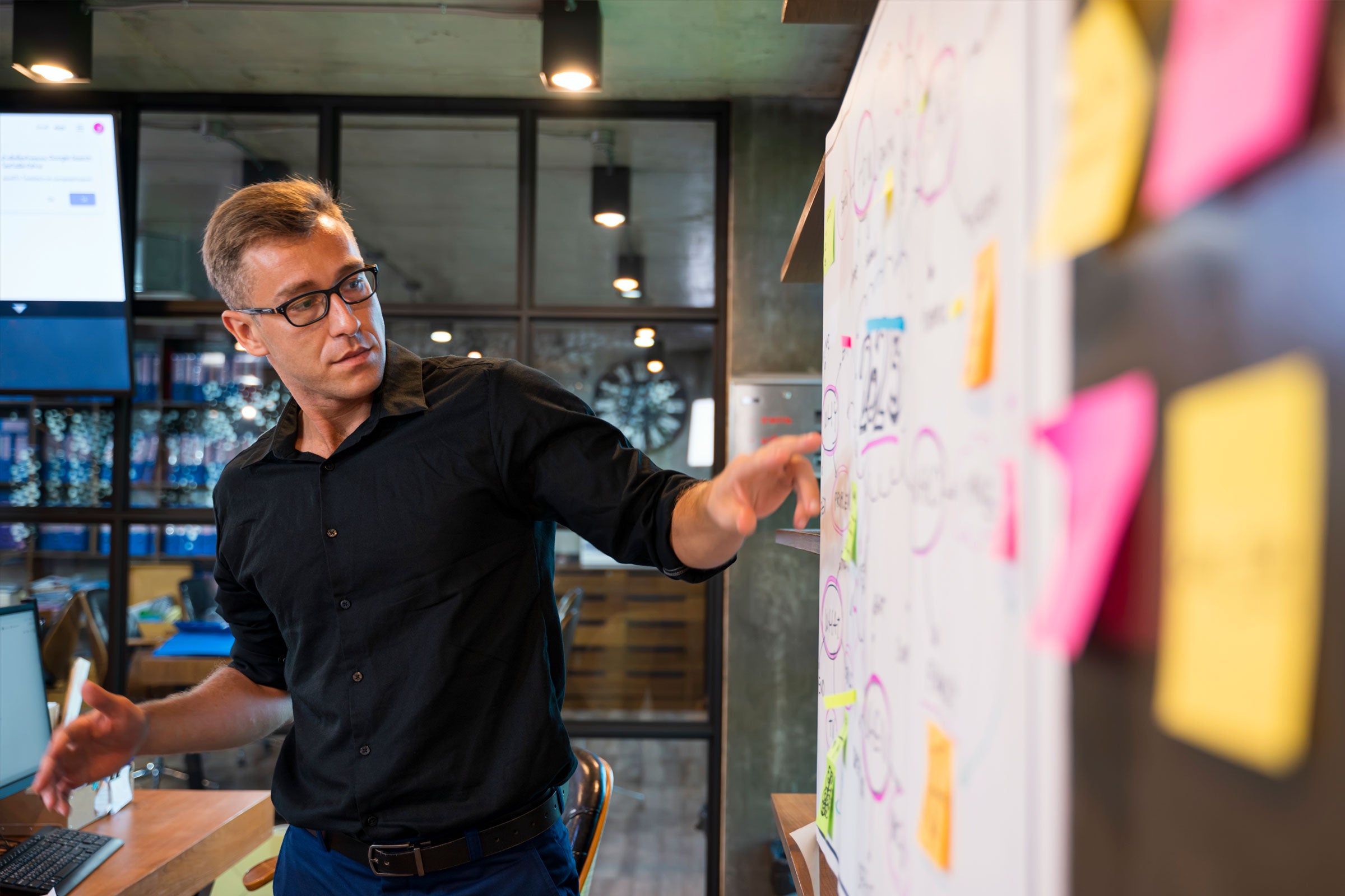 Person pointing at a whiteboard with lots of post-its on it