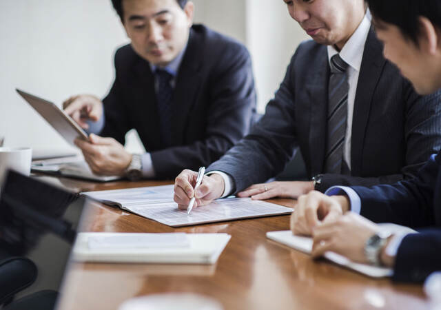 Three business professionals meeting to discuss market authorization of medical device regulations in Japan