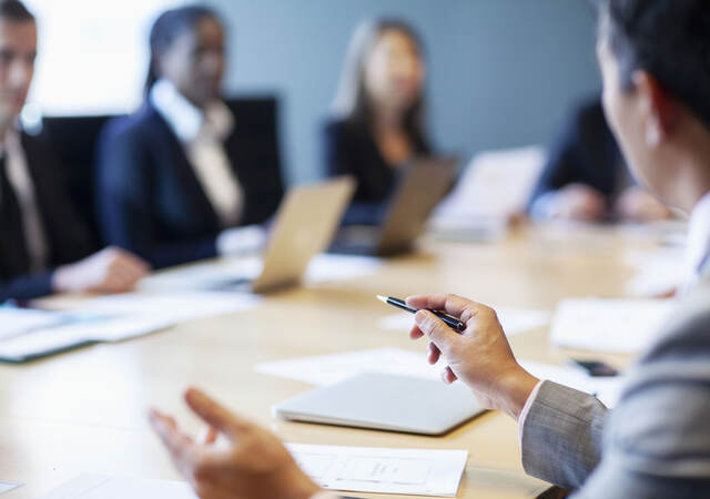 Closeup of a person gesturing ideas to work colleagues during a business meeting at board room conference table