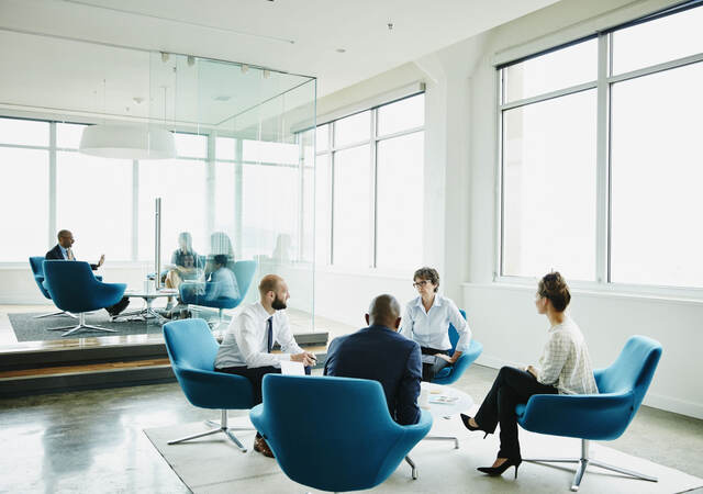 Group of business professionals having a meeting while sitting in blue chairs