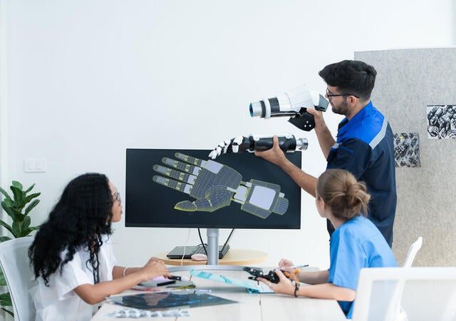 Technician reviewing a robotic hand with medical professionals