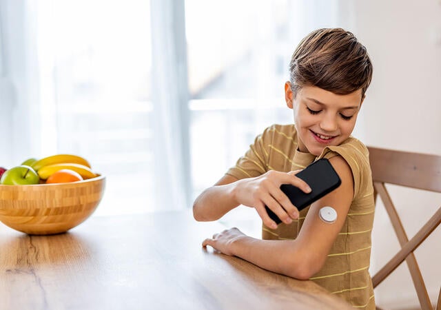 Child using a mobile device to check blood sugar levels