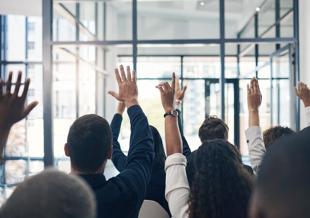 Group of people raising their hands to ask questions
