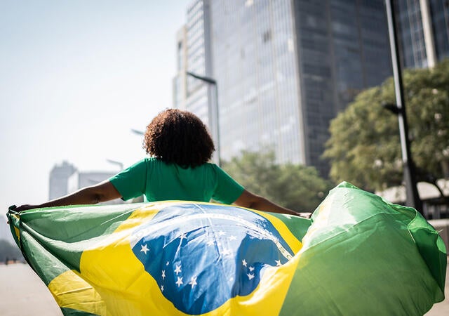 Person running through a city while holding the flag of Brazil