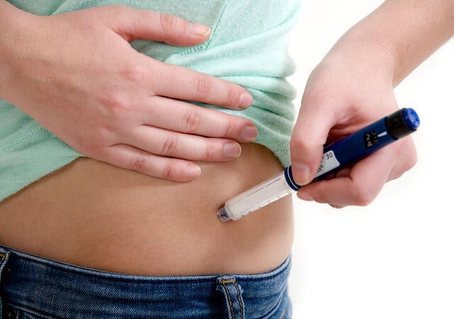 Person using an auto injector on their hip