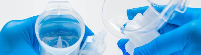 A young healthcare worker with blue gloves is preparing an asthma nebulizer on a white background