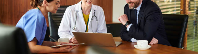 Business person sitting at a conference table with two medical professionals