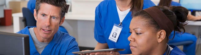 Three nurses surround a computer