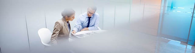 Two people reviewing a document in a conference room