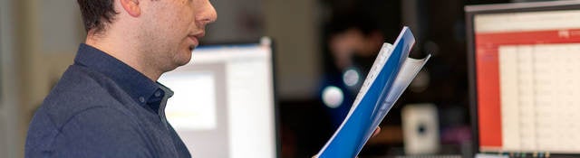 Person standing at a desk looking at documents