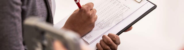 A person with a pen holding a checklist.