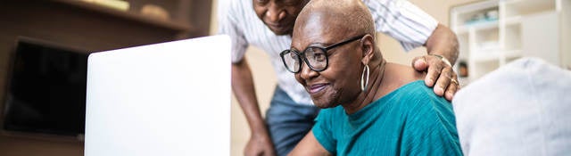 Two senior individuals looking at a laptop