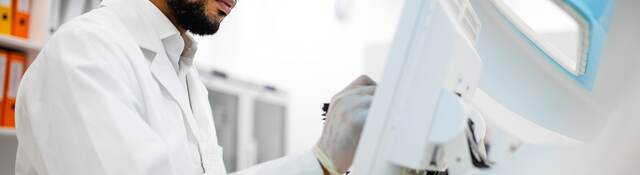 Scientist in lab coat working at the computer screen.