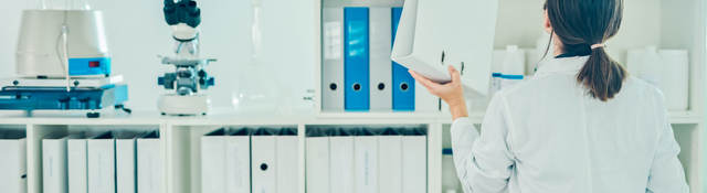 Lab tech putting away a binder on a shelf