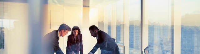 Business colleagues leaning over a table in an office while they work on their business strategy