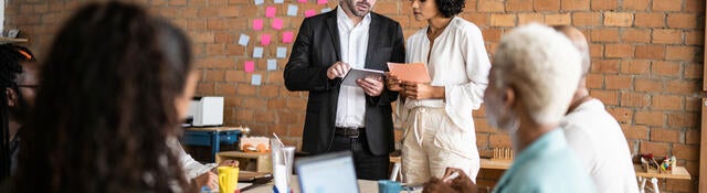 Business colleagues collaborating in front of a brick wall with post-it notes