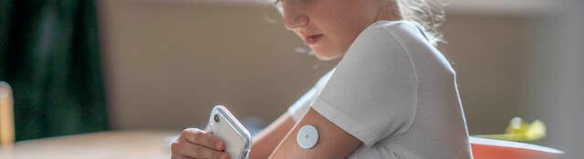 Girl monitoring medical device patch with smartphone