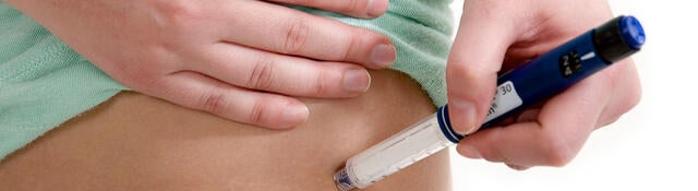 Person using an auto injector on their hip