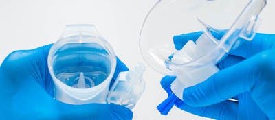 A young healthcare worker with blue gloves is preparing an asthma nebulizer on a white background