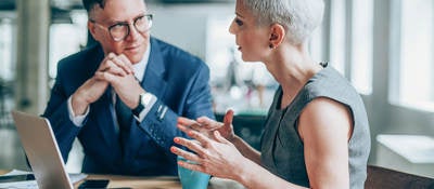 Two people having a discussion in front of a laptop 