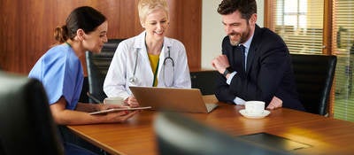 Business person sitting at a conference table with two medical professionals