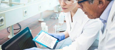 Two lab technicians looking at data on a computer