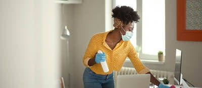 Person wearing a face mask and gloves cleaning a work desk