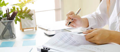 Person sitting at desk reviewing documents with a pen