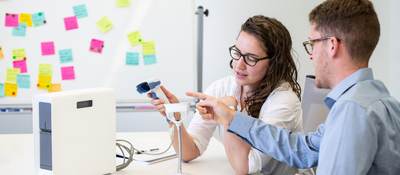 Two people in a conference room testing medical equipment