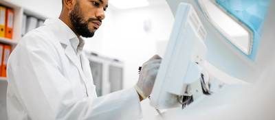 Scientist in lab coat working at the computer screen.