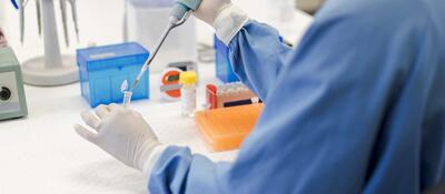 Scientist using a pipet while holding a vial