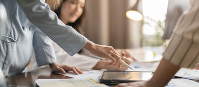 Group of business professionals having a discussion while looking at a tablet on a table