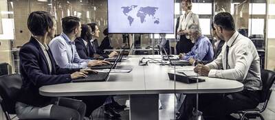 Group of business professionals having a meeting while looking at a map of the world