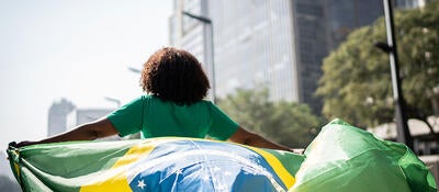 Person running through a city while holding the flag of Brazil