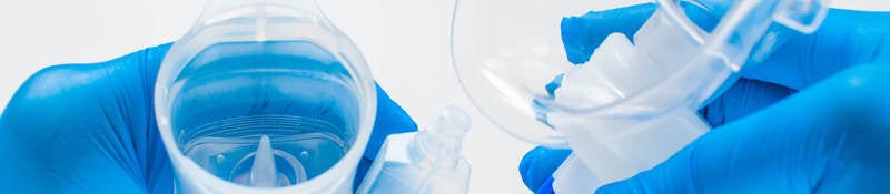 A young healthcare worker with blue gloves is preparing an asthma nebulizer on a white background