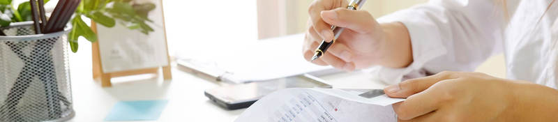 Person sitting at desk reviewing documents with a pen