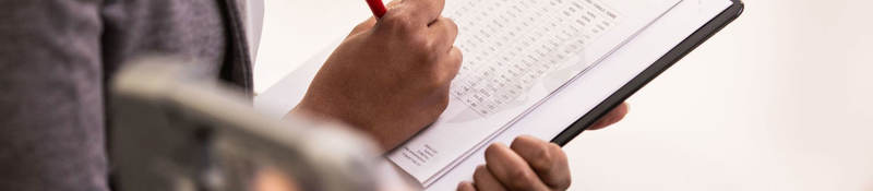 A person with a pen holding a checklist.