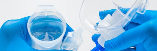 A young healthcare worker with blue gloves is preparing an asthma nebulizer on a white background