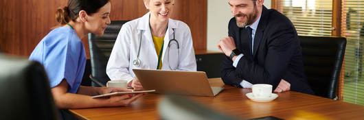 Business person sitting at a conference table with two medical professionals