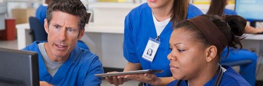 Three nurses surround a computer