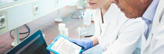 Two lab technicians looking at data on a computer