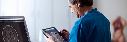 Doctor holding portable computer. Looking at MR scan image of human brain on screen