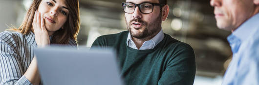 Three people looking at a laptop at work