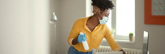 Person wearing a face mask and gloves cleaning a work desk