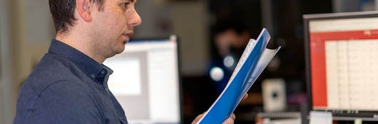 Person standing at a desk looking at documents